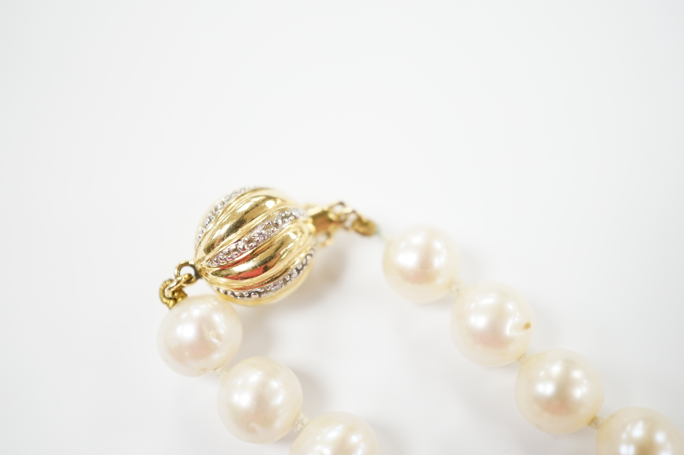 A single strand cultured pearl necklace with 18K and diamond chip set spherical clasp, 49cm.